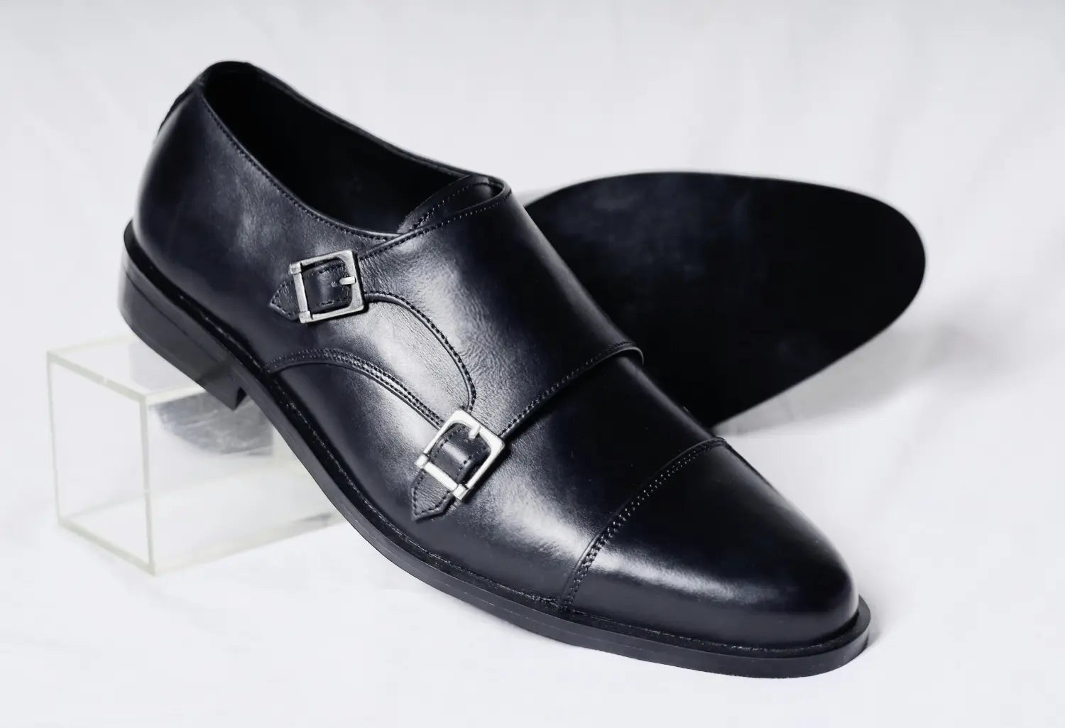 Polished black leather double monk strap shoes with a glossy finish
