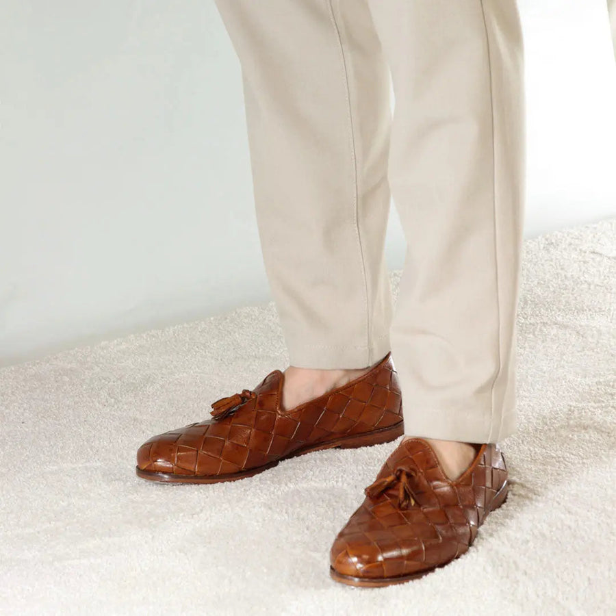 Brown woven leather tassel loafers worn with cream 